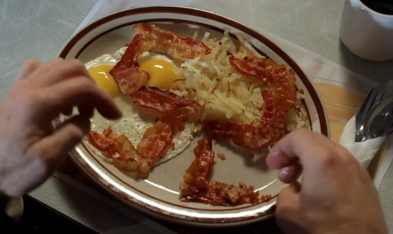 Breaking Bad scene with Walter White enjoying a birthday breakfast of bacon and eggs, symbolizing the iconic moment from the series. The bacon is arranged in the number '50' on the plate, a reference to Walter's 50th birthday, capturing a moment of normalcy before the chaos. Bacon and eggs are perfectly arranged in this simple yet symbolic dish, making it a memorable Breaking Bad moment